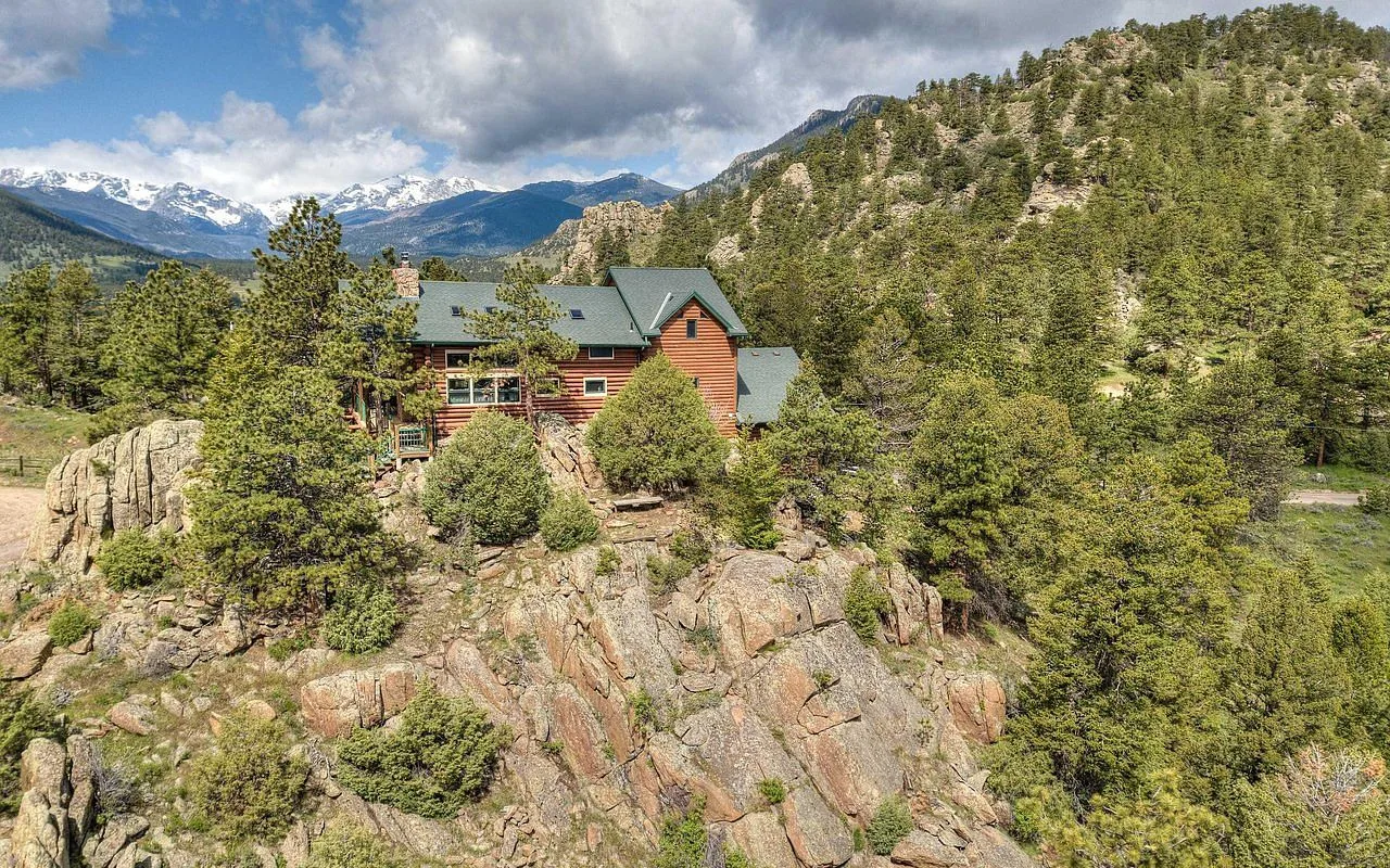 Aerial view of the Range View on the Rocks log lodge perched on a private ridge in Estes Park with snow-capped Rocky Mountain peaks in the distance