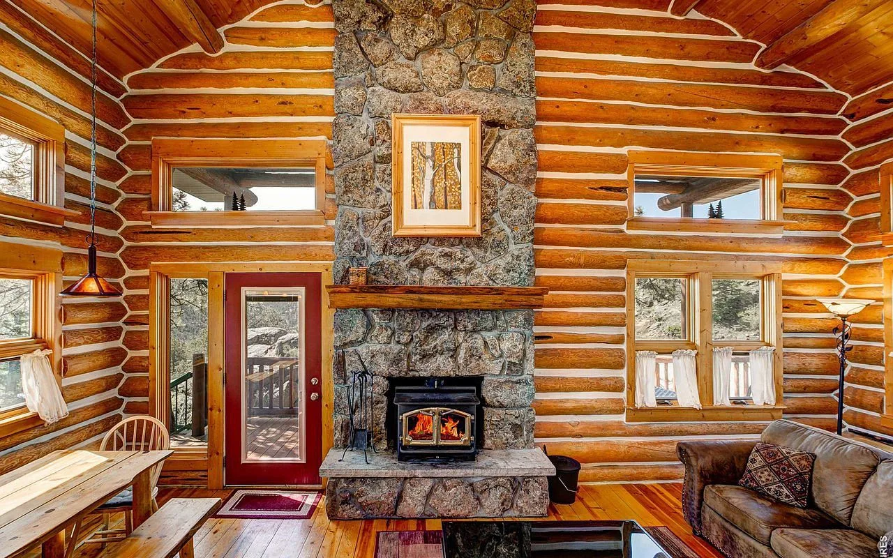 The great room fireplace: stone hearth with wood-burning stove, red door onto the deck