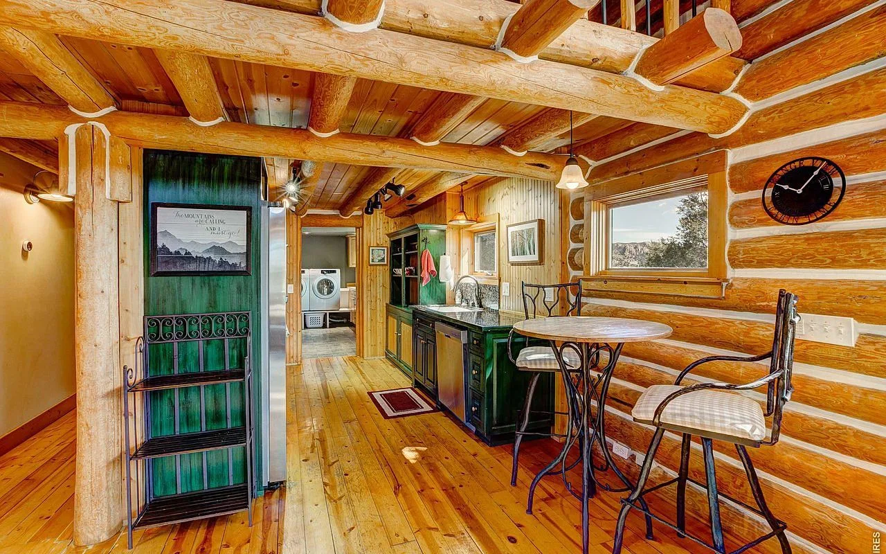Kitchen breakfast bar with green cabinets beneath exposed log beams