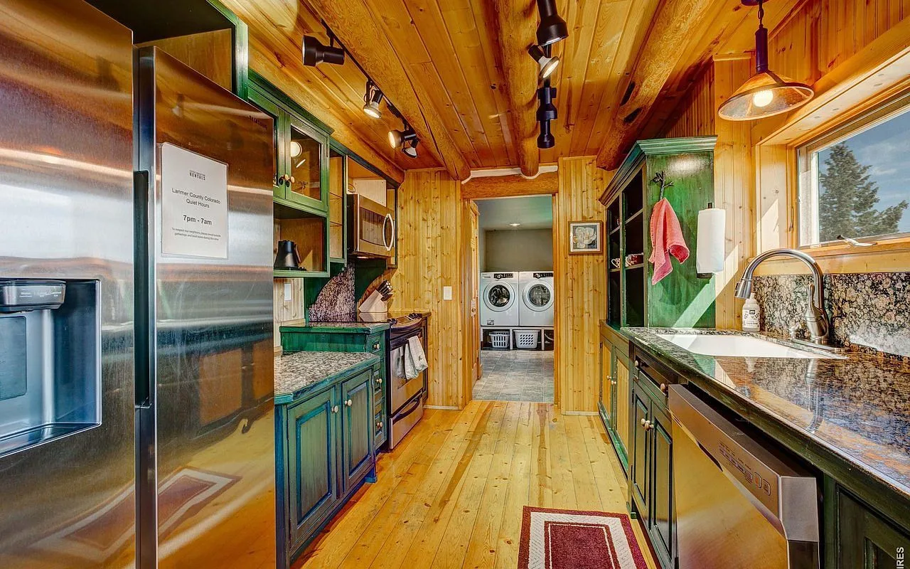Full kitchen with forest-green cabinets and stainless appliances in the Estes Park log lodge