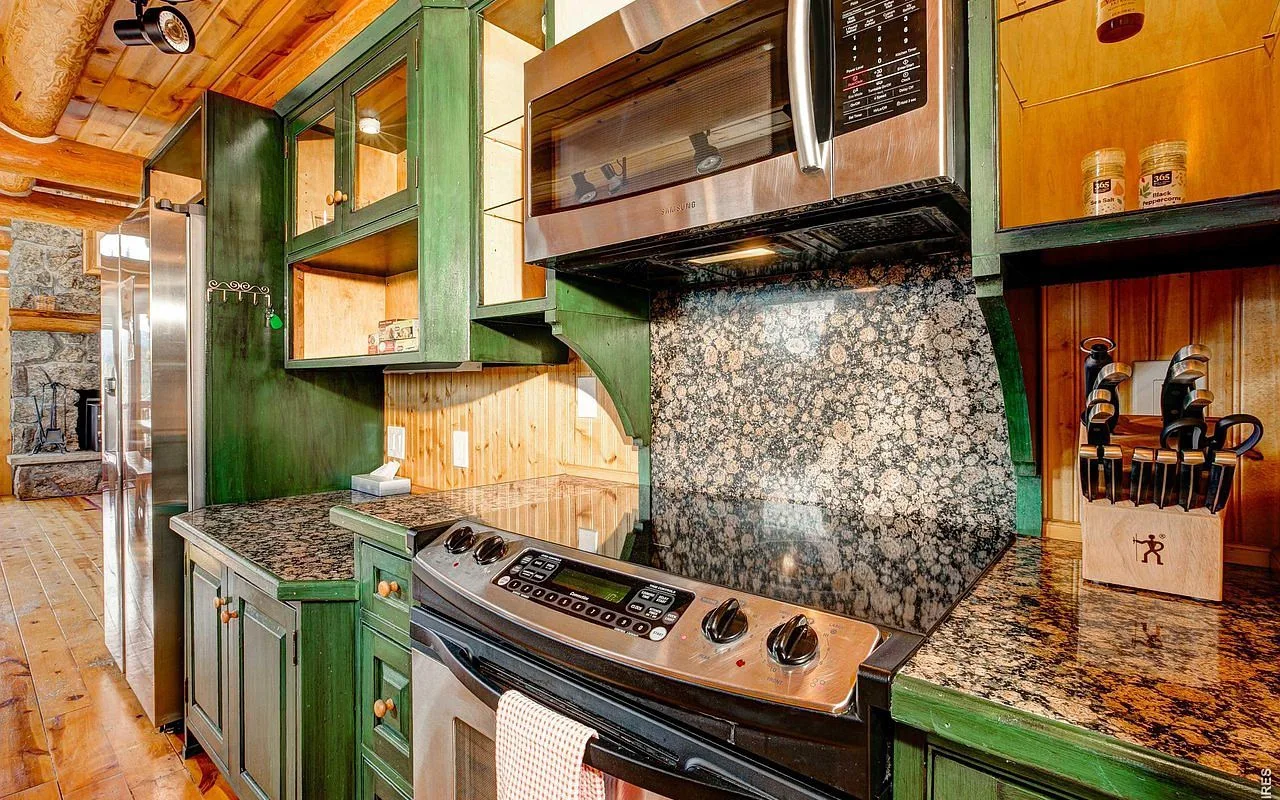 Kitchen range with granite counters and green cabinetry