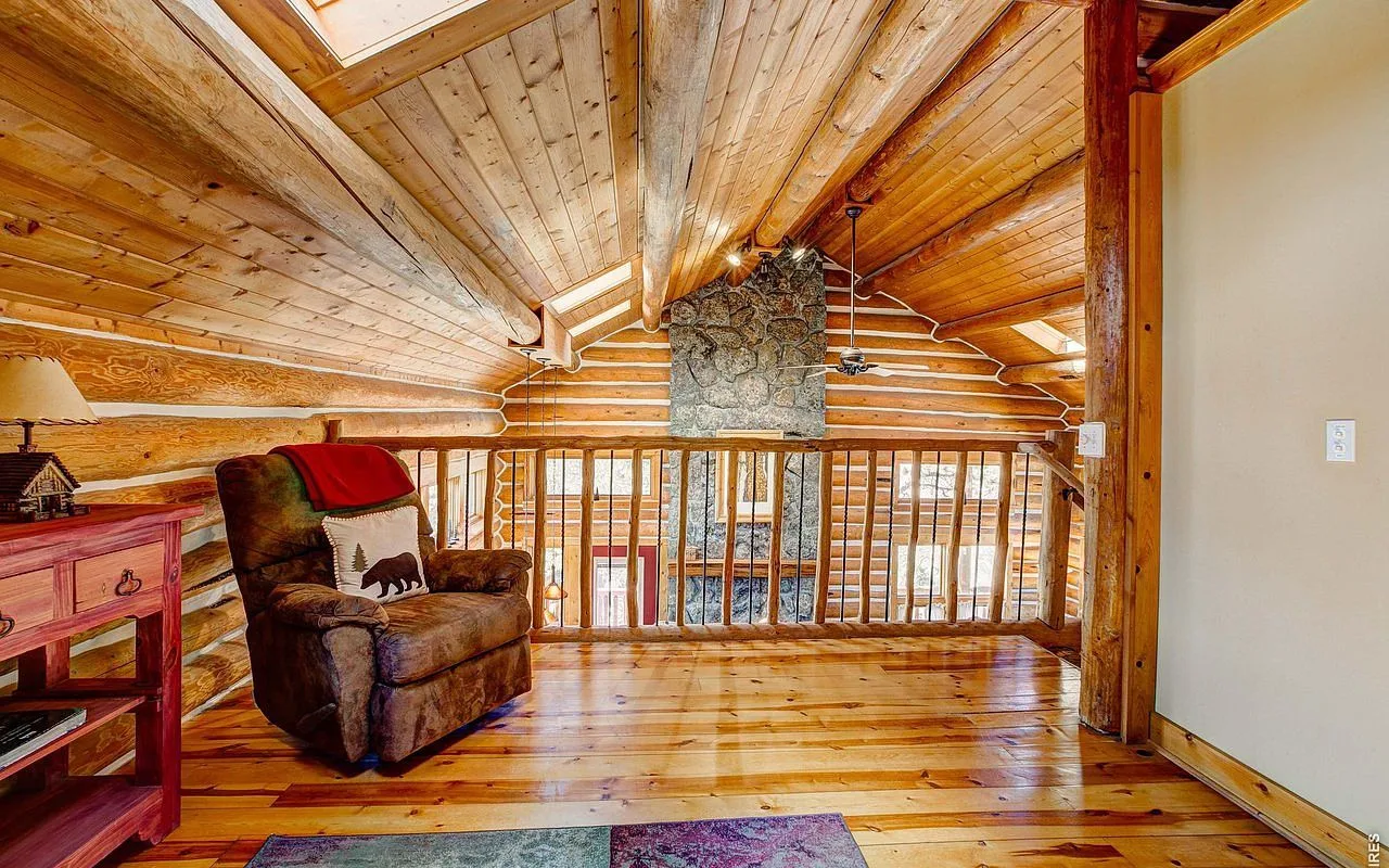 Loft library under vaulted golden-pine ceilings with a reading chair