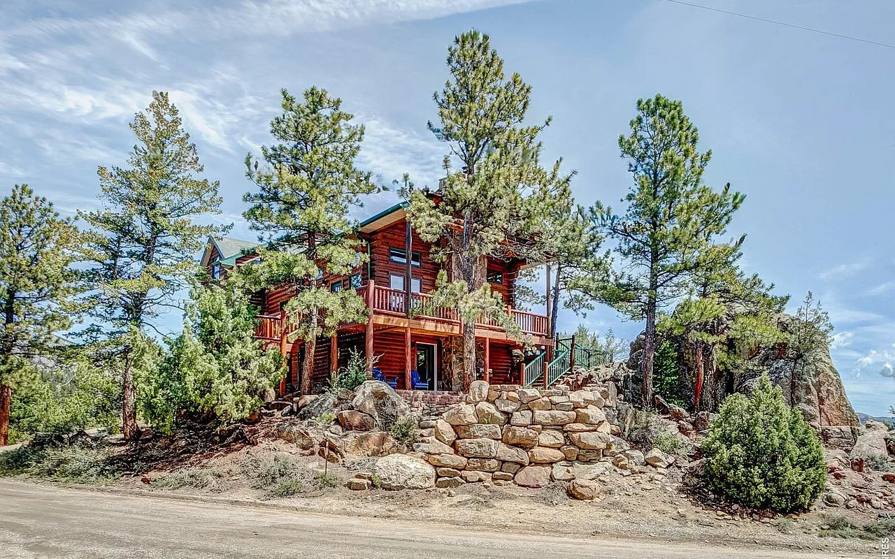 The log lodge perched on a granite outcrop above Estes Park, framed by ponderosa pines