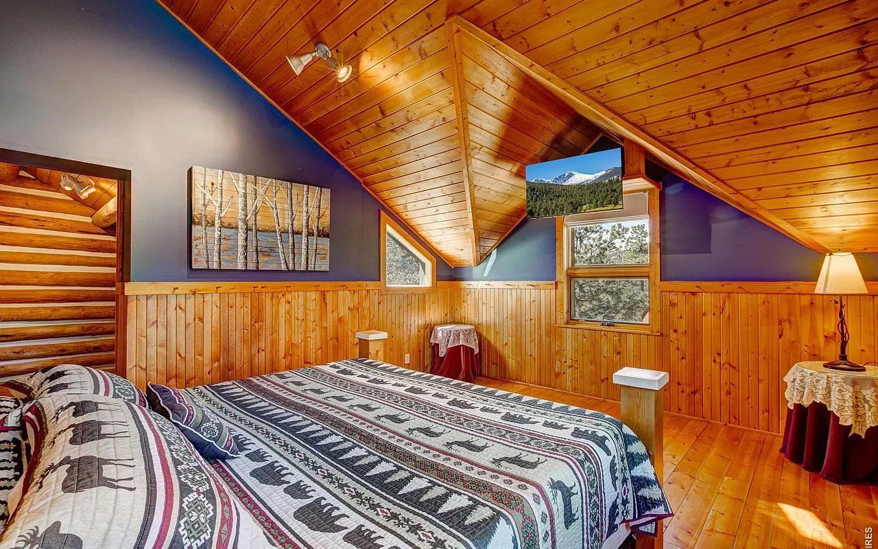 The primary bedroom with vaulted ceilings and a small mountain-view window