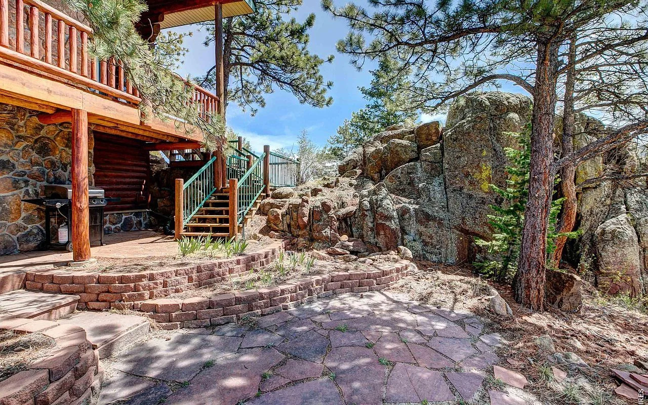 Stone patio nestled among granite boulders and ponderosa pines below the deck