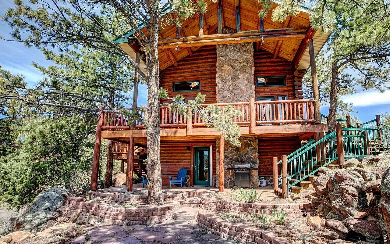 Wraparound redwood deck and stone patio of the log lodge seen from the hillside below